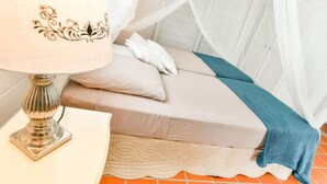 Un dormitorio con cama, mesita de noche con lámpara y dosel.