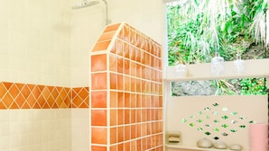 Un baño con ducha, inodoro y repisas con objetos decorativos.
