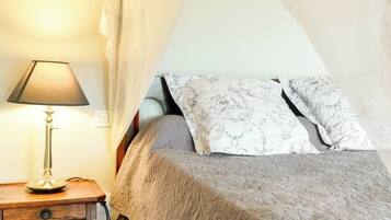 Ein Schlafzimmer mit einem Bett, einer Nachttischlampe und einem Vorhang.