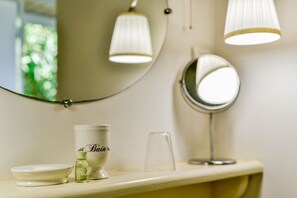 A bathroom vanity with a mirror, a glass, a bottle, and a cup.