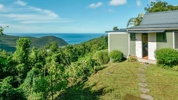 Una casa amb vistes a l'oceà, envoltada de verdor i turons.