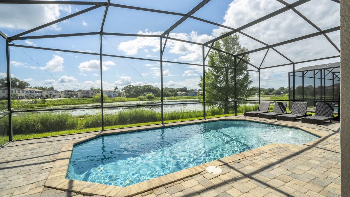A covered swimming pool with a view of a lake and buildings in the background.