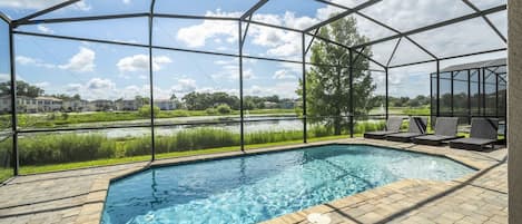 A covered swimming pool with a view of a lake and buildings in the background.
