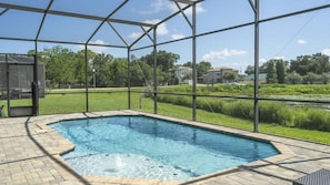 A swimming pool with a glass enclosure, surrounded by a brick patio. - Balmoral 4BR Villa Pool & Lake View Near Legoland (Haines City)