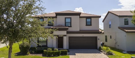 A two-story residential building with a garage, a paved driveway, and well-maintained landscaping.