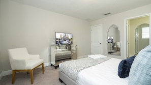 A bedroom with a bed, a chair, a dresser, a television, and a mirror. - Balmoral 4BR Villa Pool & Lake View Near Legoland (Haines City)