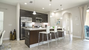 A modern kitchen with a central island, stainless steel appliances, and bar stools. - Balmoral 4BR Villa Pool & Lake View Near Legoland (Haines City)