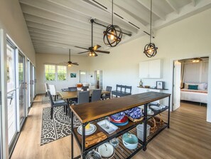 A spacious dining area with a long table, chairs, and a ceiling fan.