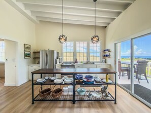 A modern kitchen with a central island, pendant lighting, and a view to the outside.