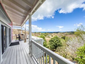 A wooden deck with a white railing, a hammock, and a table with chairs.