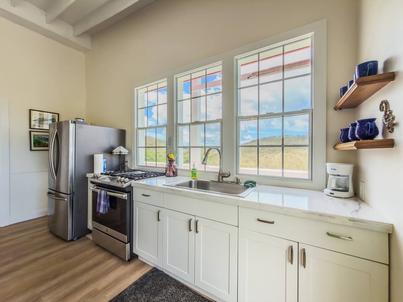 Eine Küche mit einem Edelstahl-Kühlschrank, Backofen und Spüle, mit einem Fenster mit Blick ins Freie.
