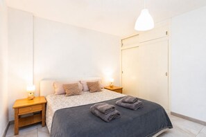 Ein Schlafzimmer mit einem Bett, zwei Nachttischen, einem Kleiderschrank und einer Hängeleuchte.