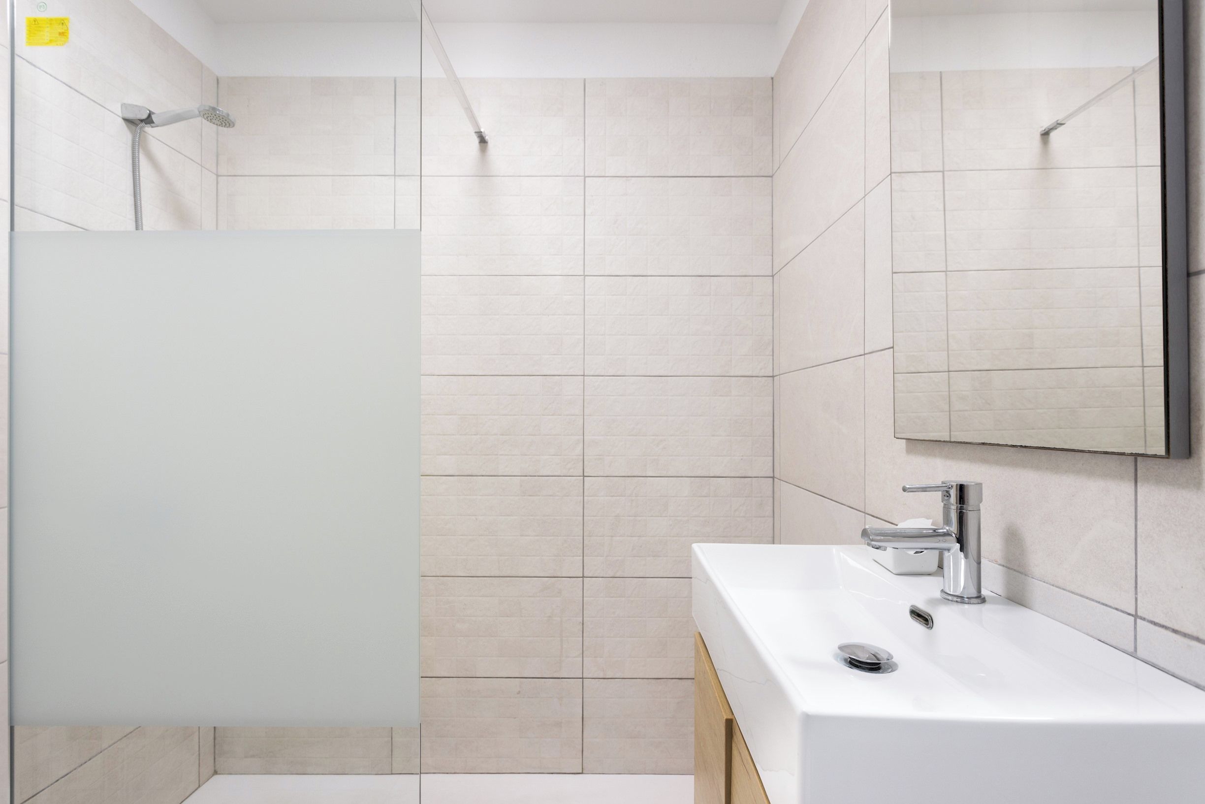 A modern bathroom with a shower, a sink, and a mirror.