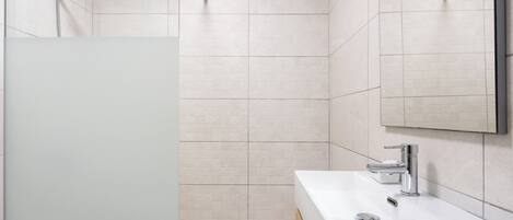 A modern bathroom with a shower, a sink, and a mirror.