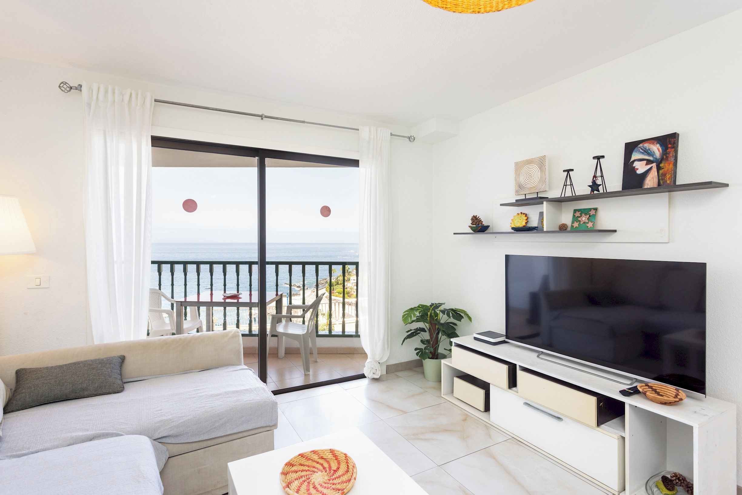 Una sala de estar moderna con sofá, televisión y un balcón con vistas.