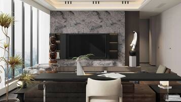 A modern living room with a large flat-screen TV mounted on a marble wall, a dark sofa, a glass coffee table, and a potted plant.