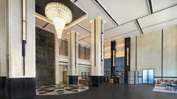 A spacious lobby with a grand chandelier, high ceilings, and a modern design.