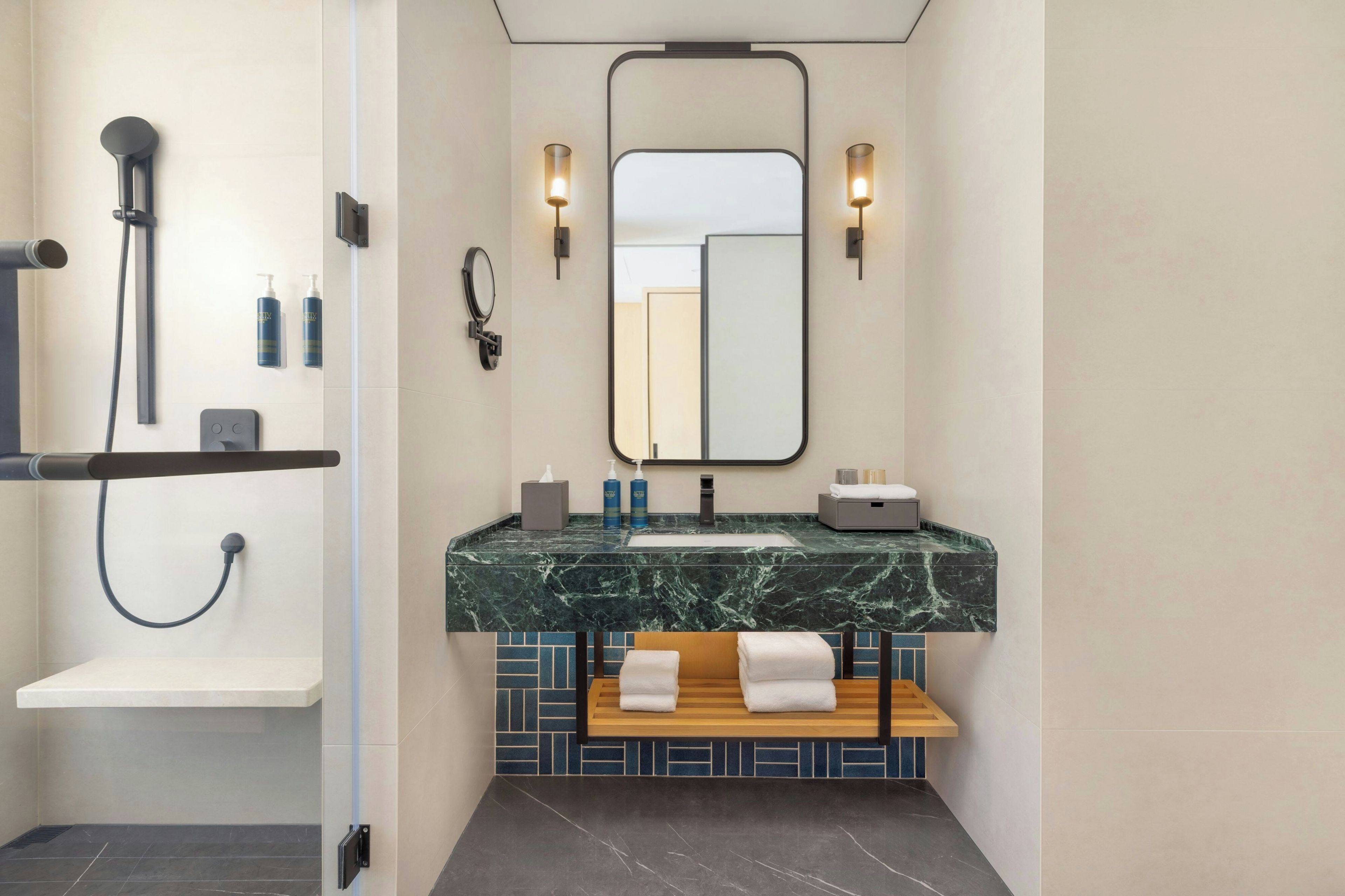 A modern bathroom with a shower, a sink with a marble countertop, and a mirror above the sink.