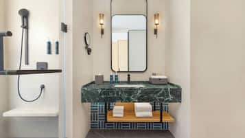 A modern bathroom with a shower, a sink with a marble countertop, and a mirror above the sink.