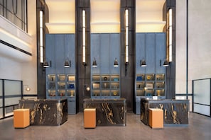 A reception area with marble counters, wall-mounted lighting, and a display of framed items. - Four Points By Sheraton Kashgar (Kashgar)