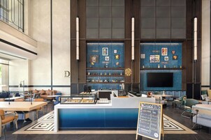 Zona de bar moderna con mostrador, asientos y una pantalla grande.