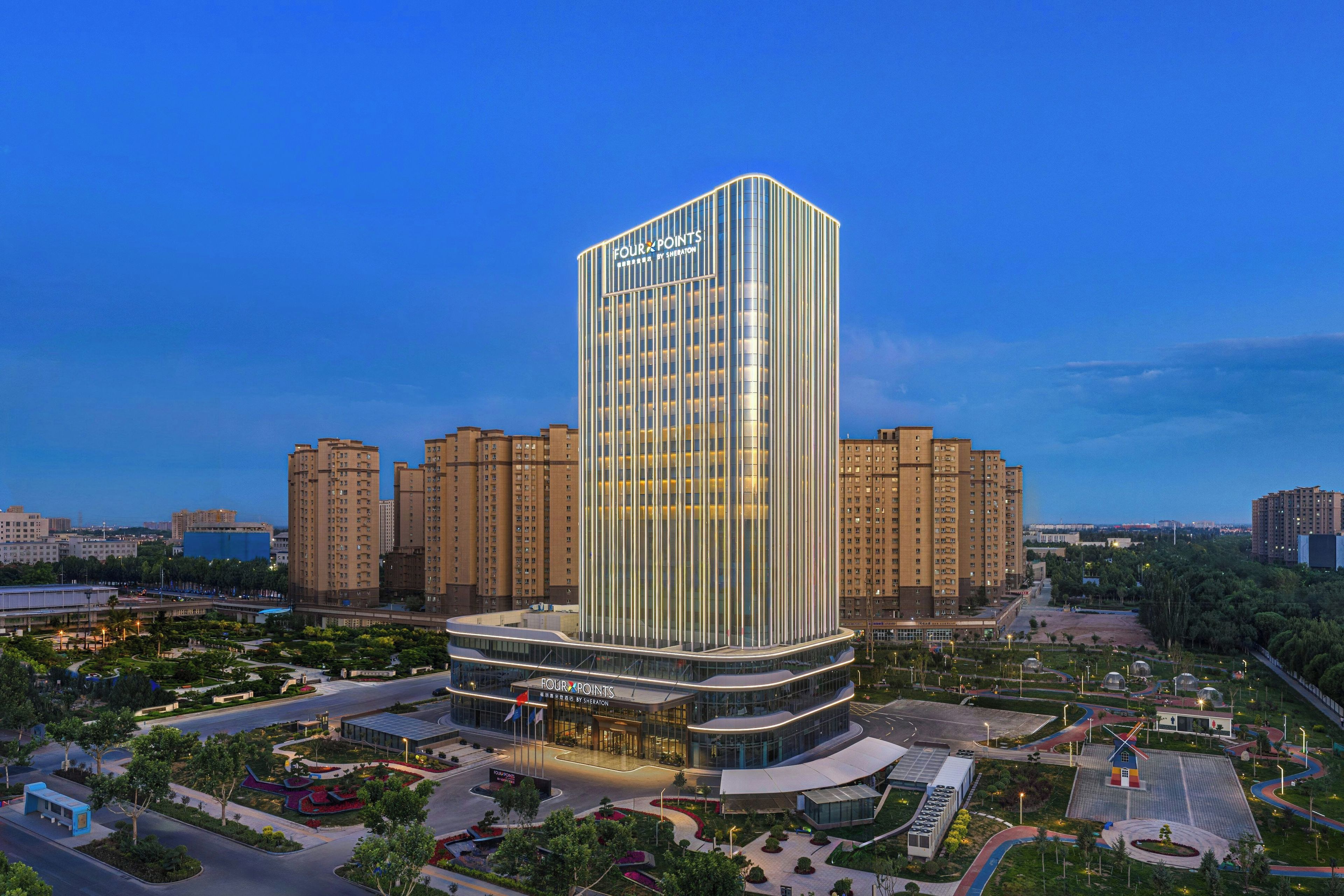 A modern hotel with a prominent vertical facade, a central entrance, and a landscaped courtyard.