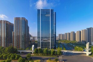A modern high-rise hotel with a glass facade, surrounded by other high-rise buildings, featuring a prominent entrance with a bridge and landscaped areas. - Fairfield By Marriott Nanjing Yuhuatai (Nanjing)