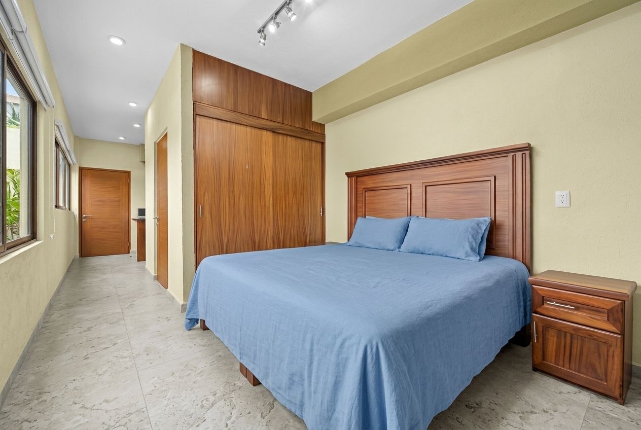 A bedroom with a large bed, wooden wardrobe, and a nightstand.