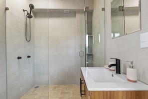 Ein modernes Badezimmer mit Dusche, Waschbecken und Spiegel.
