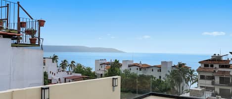 Una terraza en la azotea con vistas al mar y edificios circundantes.