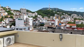 A densely packed urban area with various buildings, including residential and commercial structures, and a prominent hill with a tower in the background. - Sol & Sal Studio Steps to Beach & Malecon (Puerto Vallarta)