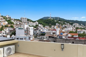 Ein dicht bebautes Stadtgebiet mit verschiedenen Gebäuden, darunter Wohn- und Geschäftsgebäuden, und einem markanten Hügel mit einem Turm im Hintergrund.