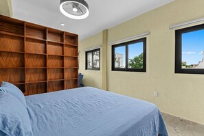A bedroom with a bed, a wooden shelving unit, and two windows. - Sol & Sal Studio Steps to Beach & Malecon (Puerto Vallarta)