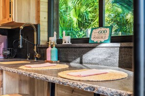 A kitchen counter with a coffee station, a water fountain, and a sign with a motivational quote.