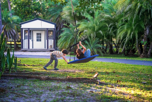 A residential area with a house, a swing set, and lush greenery.
