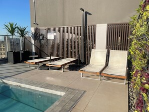 A rooftop pool area with lounge chairs, a pool, and a fence. - Modern studio in the city center | Pool + Gym | Subway (São Paulo)