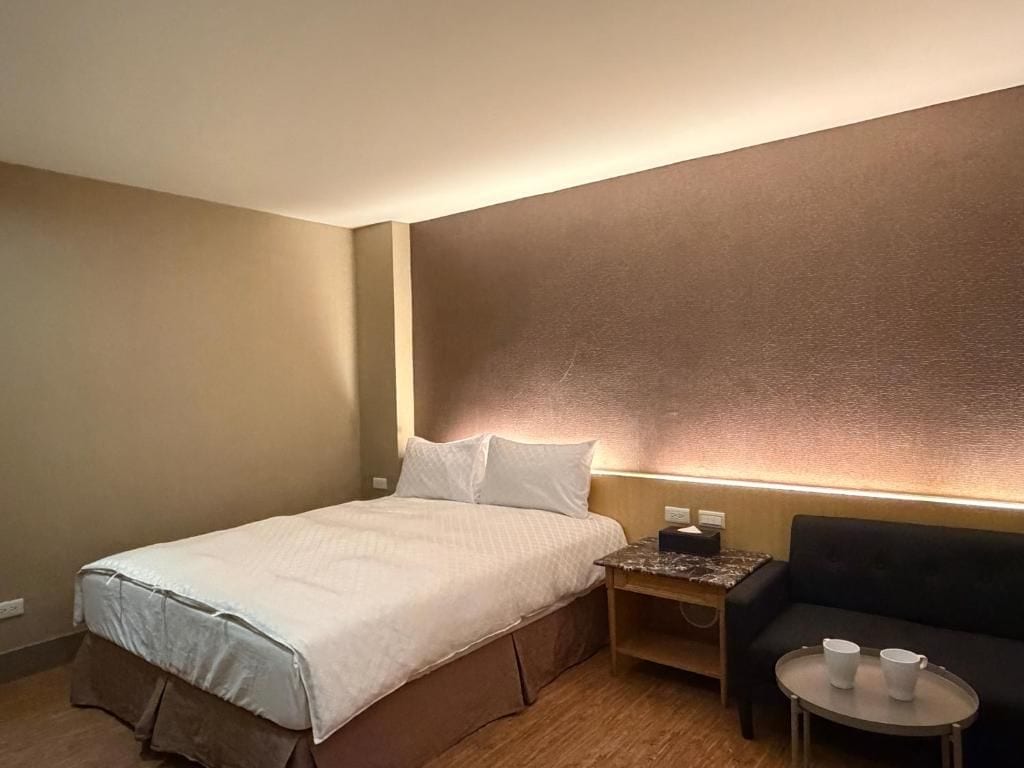 Une chambre d’hôtel avec un lit, une table de chevet, une table avec deux tasses et un canapé.