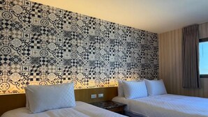 Quarto de hotel com duas camas, parede estampada e janela com cortinas.