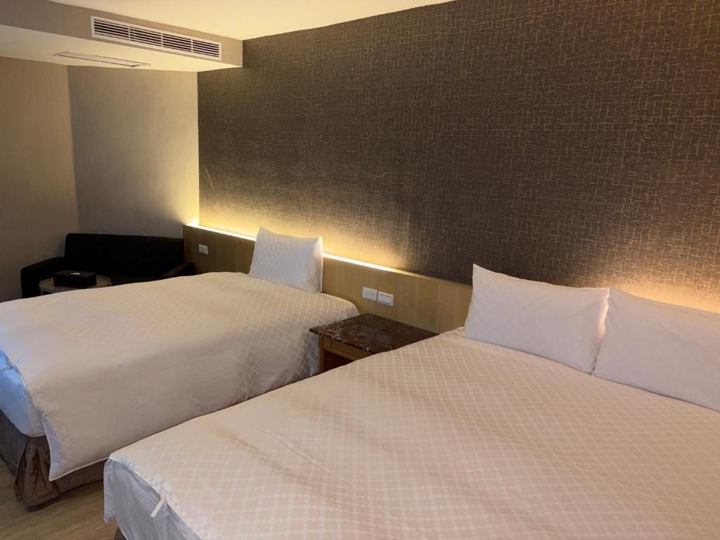 Hotellihuone, jossa on kaksi sänkyä, sängynpääty ja yöpöytä.