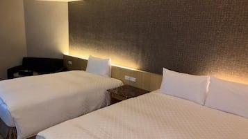 Hotellihuone, jossa on kaksi sänkyä, sängynpääty ja yöpöytä.