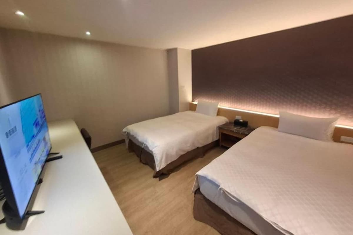 Habitació d'hotel amb dos llits, un escriptori amb un ordinador i una televisió penjada a la paret.