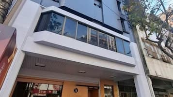 A modern building with a prominent entrance, large windows, and a sign indicating a hotel.