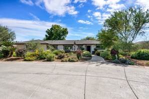 A residential house with a driveway, surrounded by various plants and trees. - Olive Ranch: a Beautifully Landscaped Family Home (Clovis)