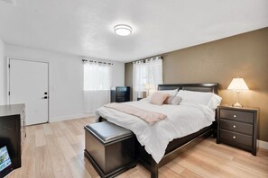 A modern bedroom with a bed, bedside tables, a desk, and a lamp. - Olive Ranch: a Beautifully Landscaped Family Home (Clovis)
