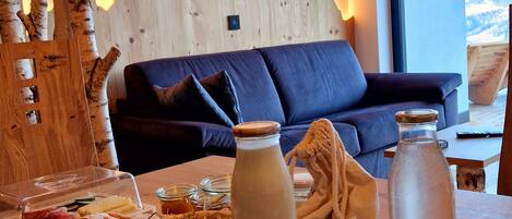 Een gezellige woonkamer met een houten accentmuur, een bank en een eettafel met eten erop.