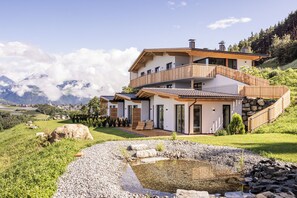 A modern two-story house with a balcony, surrounded by a well-maintained garden and a view of mountains. - Charming 2-Bedroom Chalet at Stabingerhof Farm, South Tyrol (Trentino-Alto Adige)