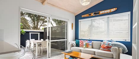 Uma sala de estar moderna com um sofá, mesa de centro e uma área de jantar com cadeiras.