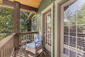 A covered porch with a wicker chair and a small table, a wooden railing, and a sliding glass door. - Buffalo Peaks - Where your Adventure Begins (Driggs)