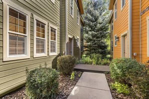 A residential building with a narrow pathway leading to the entrance, flanked by greenery and a small wooden deck. - Buffalo Peaks - Where your Adventure Begins (Driggs)