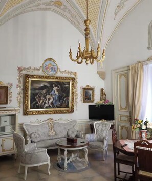 A room with a grand chandelier, a large framed painting, and ornate furniture. - The Count's House (Parabita)